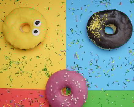 round different donuts with sprinkles on a bright multi-colored background photo