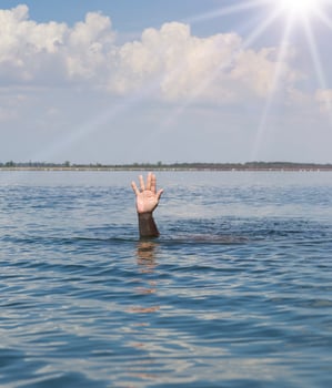 man's hand sticks out from the water in the middle of the ocean photo