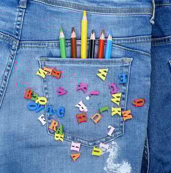 multicolored wooden letters of the English alphabet are scattered on blue jeans photo