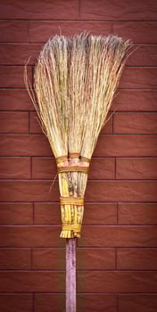 broom on a wooden handle stands near a brick wall photo
