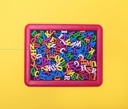 multicolored wooden letters of the English alphabet in a red frame photo
