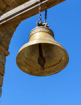 a large copper bell hanging on a wooden crossbeam photo