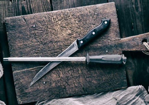 old knife and a sharpener on a brown wooden cutting board photo