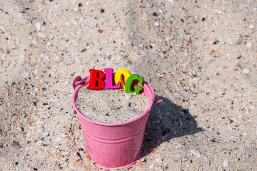 Word blog of wooden letters in a pink bucket with sand photo