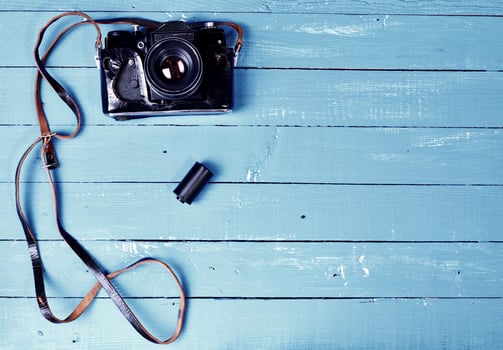 Vintage film camera in a leather case on a blue wooden surface photo