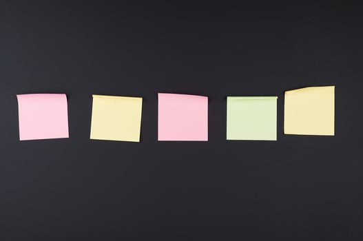 empty square multi-colored stickers hang on a black board photo