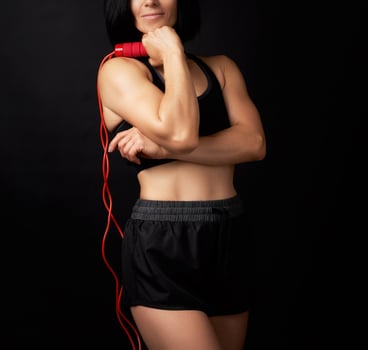 young woman with a sports figure in black uniform holds a red rope for jumping photo