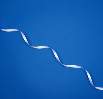 white silk thin ribbon twisted on a blue background photo