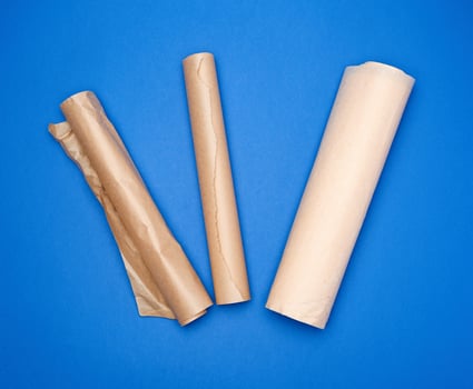 three rolled rolls with brown parchment baking paper on a blue background photo