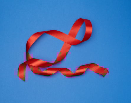 red silk thin ribbon twisted on a blue background photo