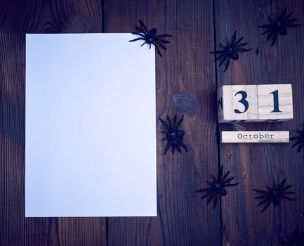 empty white paper, black spider figurines and wooden retro calendar photo