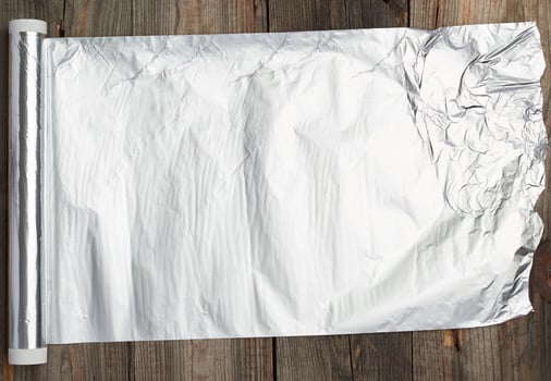 roll of gray foil for baking and packaging food on a wooden background photo