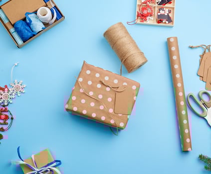 wrapping boxes in festive brown paper, next to the luggage box decor on a blue background, top view. Christmas holiday concept photo