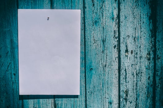 white sheet of paper hangs on a blue wooden wall photo
