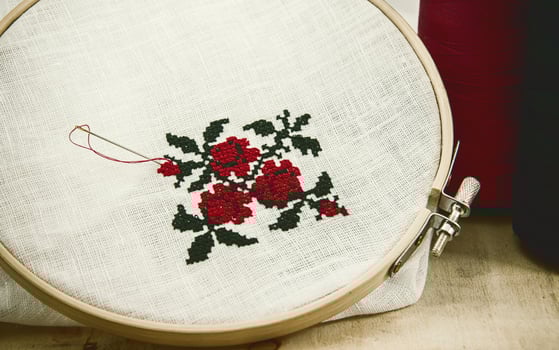 Hand embroidery cross-stitch flower ornament on a white fabric photo