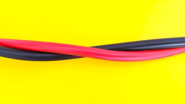 Close up view of red and black electric cables isolated on yellow background photo