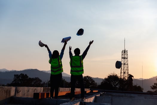 Silhouette image of engineer civil and construction worker throw up safety helmet and construction drawing against the background of surreal construction site in twilight or dark cityscape. photo