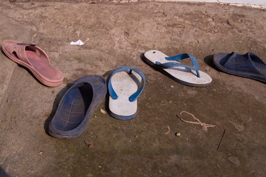 worn sandals scattered on the ground photo
