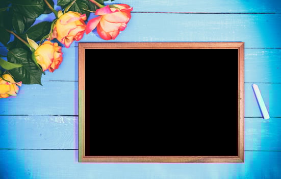 Empty black board and bouquet of yellow roses photo