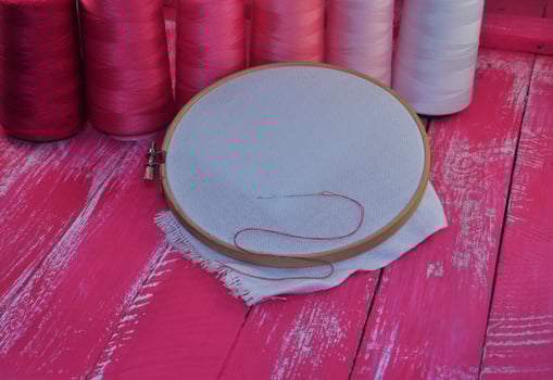 canvas in wooden hoop for embroidery on a pink background photo