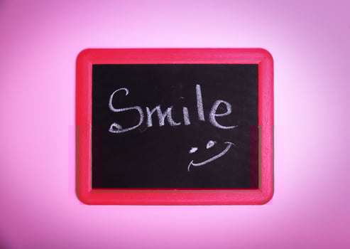 Chalkboard with an inscription smile on a pink surface photo