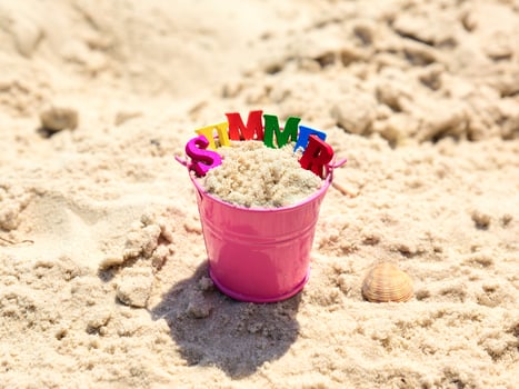 Pink baby bucket with sand and inscription summer photo