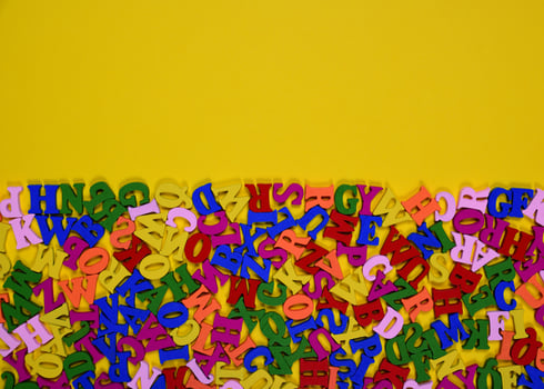 Wooden multicolored letters of the English alphabet on a yellow surface photo