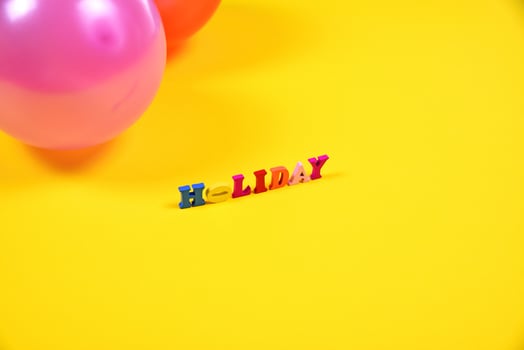 Inscription holiday of small wooden letters on a yellow surface photo