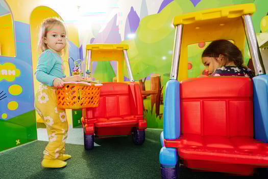 Sisters playing at indoor play center playground , girl in toy car. photo