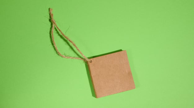 Brown paper square paper tag with rope on green background photo