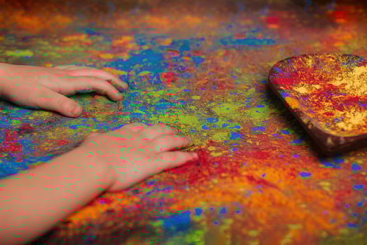 children's hands lie on a table on which Holly's paints are scattered and a wooden plate in the shape of a heart, in which bright colors, copy space. Indian festival of colors Holi. photo