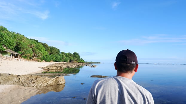 Back of man wearing a hat who is looking at the blue beaches, islands and beautiful blue sky photo