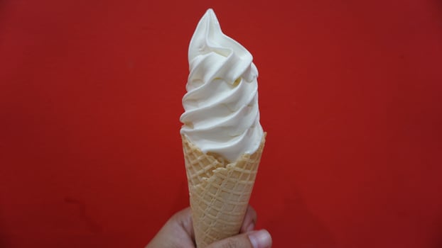 A hand holding a waffle cone with whipped cream photo