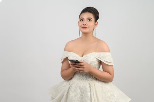 Young asian beautiful bride posting with smartphone in hand photo