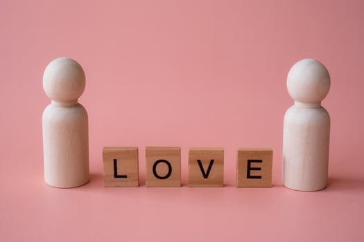 Letter words of love between wooden figurines of man and man on pink background. Love LGBTQ concept. Sexual minorities and communities concept photo