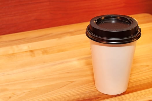 Disposable glass of coffee on a wooden table photo