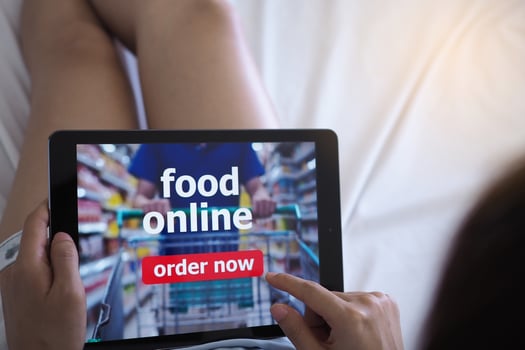 Women use tablets to order food online while lying on the couch at home. photo