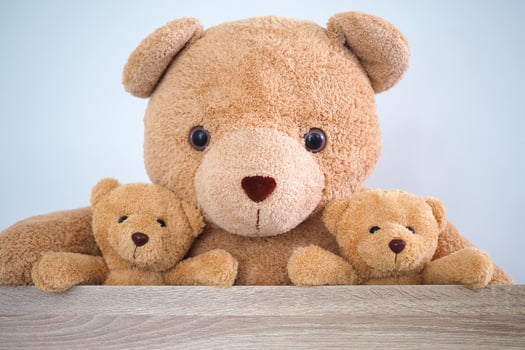 Brown teddy bear family sitting together in a chair in the room. photo