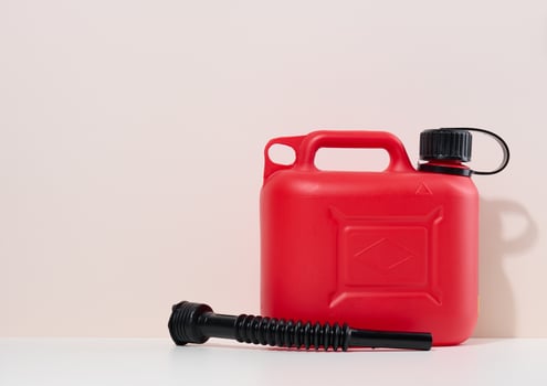 Red plastic canister for liquid fuels and lubricants on a beige background photo