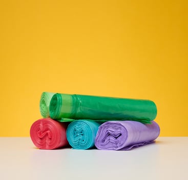 Stack of disposable plastic trash can bags on a yellow background photo