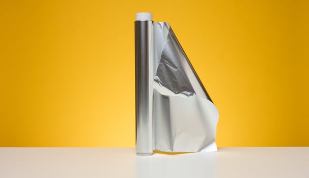 Roll of twisted food foil for packaging food on yellow background photo