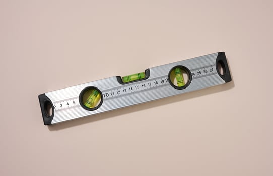 metallic building level on a beige background. Measuring instrument photo