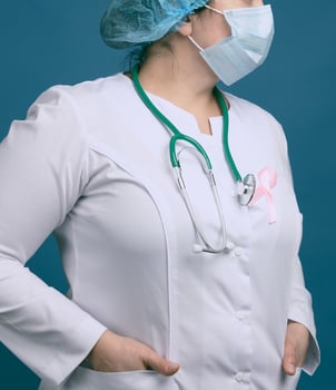 medic woman in white coat, pink ribbon pinned to the robe, symbol of the fight against breast cancer in October photo
