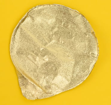 round golden aluminum thin lid for plastic yogurt jars on a yellow background photo