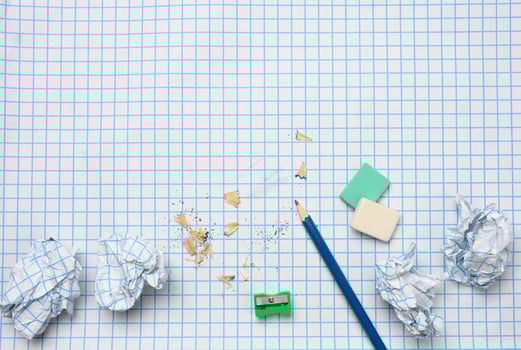 crumpled paper balls and a sharpened wooden pencil with shavings on a checkered paper sheet photo