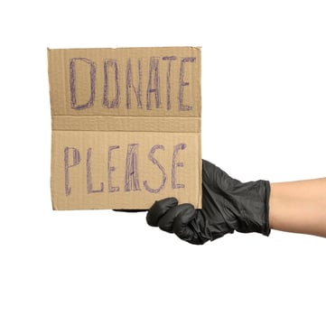 hand holding a brown piece of cardboard with the inscription please donate photo