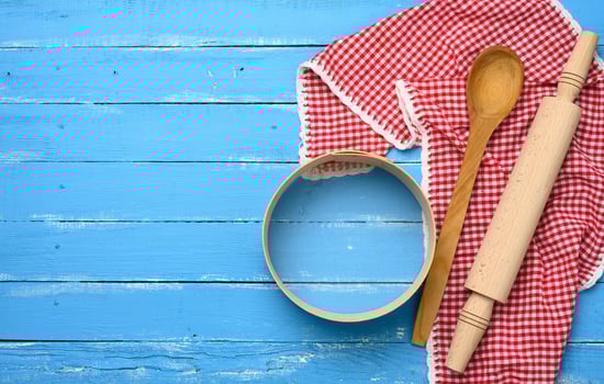 wooden rolling pin, round wooden sieve on blue background with red napkin photo