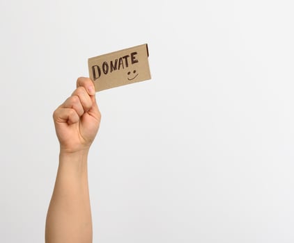 female hand holding a piece of paper with the inscription donate photo