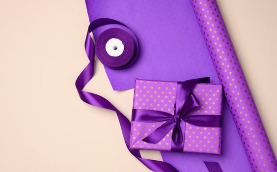 gift boxes tied with purple silk ribbon on an beige background, top view photo