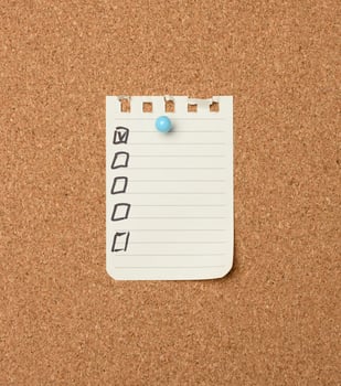 blank sheet of paper in a line attached with a plastic button on a brown cork board photo